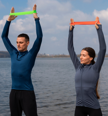 This image shows two people, a man and a woman, exercising outdoors with resistance bands. The image is a stock photo available on websites like Freepik for various uses, including health and fitness articles. Resistance bands are a popular, versatile tool for strength training, improving balance, and enhancing flexibility without heavy weights.